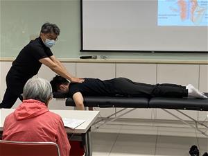 尹醫師示範用手掌的力量，對患者背部的肌肉捏、放、捏進行治療