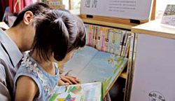 收容人陪孩子一起挑書，一起閱讀；彼此之間享受過去從未有過的心靈交流。（新北市立圖書館萬里分館提供）
