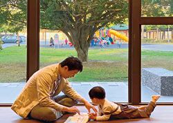 臺中市立圖書館李科永紀念圖書分館中親子一起閱讀，館外則緊鄰綠地與大型遊具。