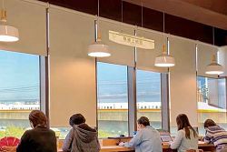 坐在臺中市立圖書館溪西分館靠窗戶位置，能看見高鐵與戶外景色。