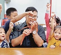 新北市立圖書館三峽分館開設「走！走！走！圖書館學習趣」課程，孩子圍在臺灣昆蟲館講師盧鋆軒旁，近距離觀察玉米蛇。