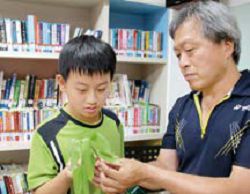 蝴蝶專家吳啟仁帶阿勃勒樹葉，讓孩子觀察葉面上的臺灣黃蝶卵。（臺中市立圖書館葫蘆墩分館提供）