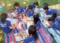 小朋友在綠地上或坐或臥閱讀課外書，充分享受閱讀派對的樂趣。（臺東縣政府文化處圖書管理科提供）