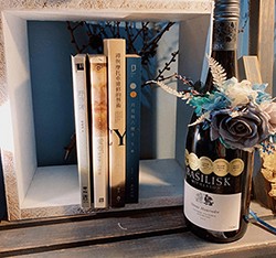 也許閱讀的過程中也想搭配點味蕾的饗宴吧？書架上放置加上永生花裝飾的紅酒瓶，實用與美觀兼具的小巧思。