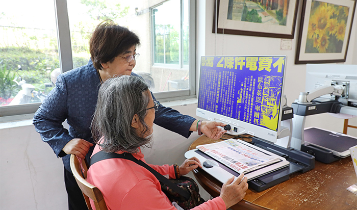 鎮長吳秋齡（左）協助長者使用桌上型擴視機，樂齡族閱讀更輕鬆。
