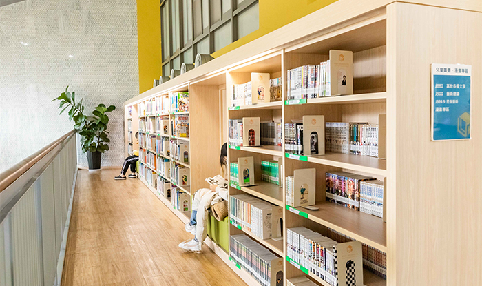 挑空閱覽區為階梯式平台，嵌入牆壁的書櫃放著漫畫與各式書籍。