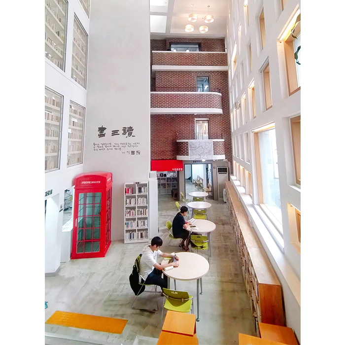 九山洞圖書館村的挑高大廳，原建築的紅磚壁面搭配寫著「書三讀」的白牆。