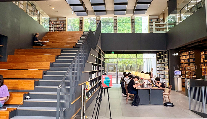 獨山圖書館大廳明亮開放,視野可見館舍後方的綠意,左側為階梯座位區。