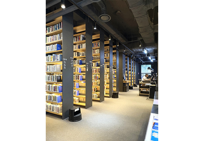 由10層高密度書架組成的綜合資料區，灰色書架間隱約透出溫暖的光線。