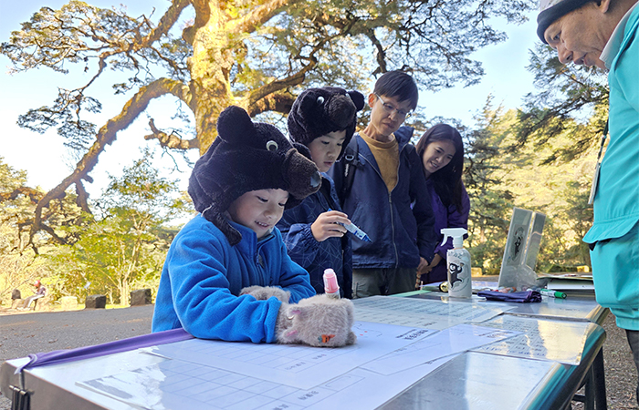 臺灣黑熊保育駐點解說於「塔塔加大鐵杉」與遊客互動。（攝影╱許明鎮）