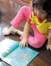 小朋友坐在親子閱覽區中,隨意地沉浸在書中的美妙世界。