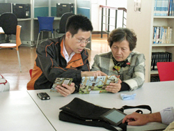 政軒館長正認真教導樂齡讀者使用平板電腦。﹙雲林縣東勢鄉立圖書館)