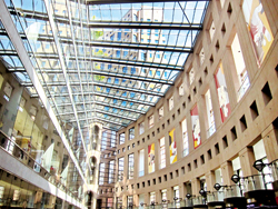 入口前與商店間形成的弧形走廊，天花板使用透明材質，在陽光的照耀之下形成了明亮的空間。