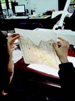 古籍修復人員仔細檢視修補後的狀況。