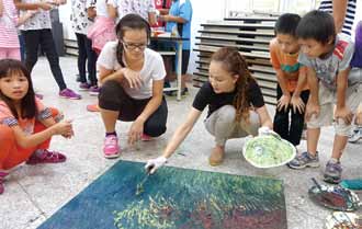 配合「深耕計畫」規劃藝術進入校園，藝術家在花蓮縣西林國小畫畫吸引小朋友圍觀。（誠品文化藝術基金會提供）